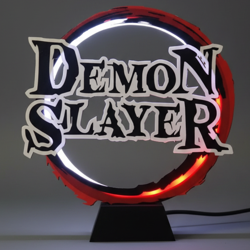 A decorative tabletop sign featuring the words 'DEMON SLAYER' in large black stylized letters with white outlines, set against a glowing red circular ring and illuminated white ring on a black base.