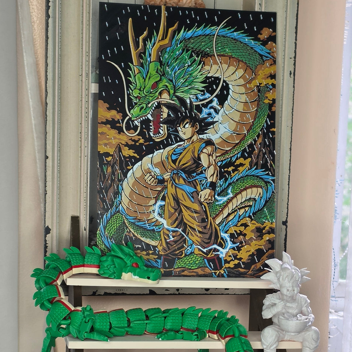 A green segmented robotic dragon curled around a rectangular black dragon figurine with a gold and blue body, displayed on a shelf next to a white dragon statue.