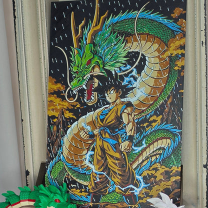 A green articulated toy dragon spine model displayed next to a colorful dragon painting on a shelf.